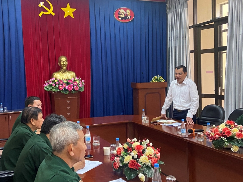 A person standing in front of a table with people sitting around itDescription automatically generated