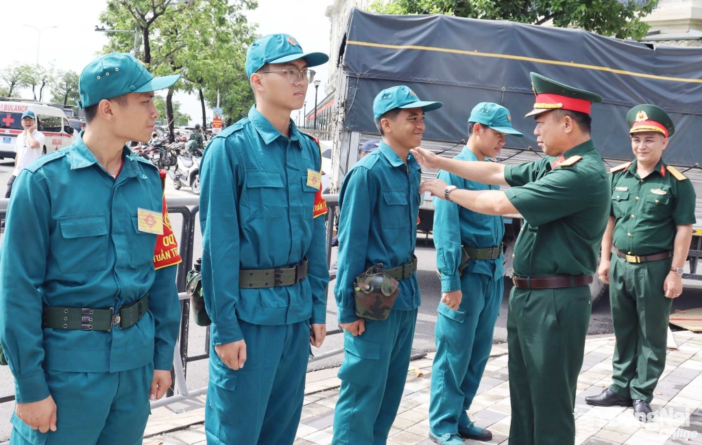 Thượng tá Phạm Minh Trí kiểm tra chấn chỉnh quân phục cho lực lượng dân quân thường trực đảm bảo an toàn phòng cháy gần khu vực lễ. Ảnh: Nguyệt Hà