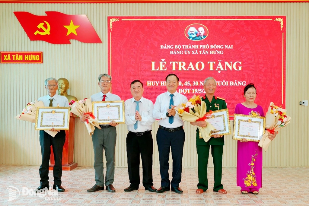 Đồng chí Mạc Đình Huấn, Bí thư Đảng ủy, Chủ tịch HĐND xã Tân Hưng  và đồng chí Nguyễn Quốc Cường, Phó Bí thư Thường trực Đảng ủy xã trao Huy hiệu Đảng và tặng hoa chúc mừng 4 đồng chí. Ảnh: Quý Son