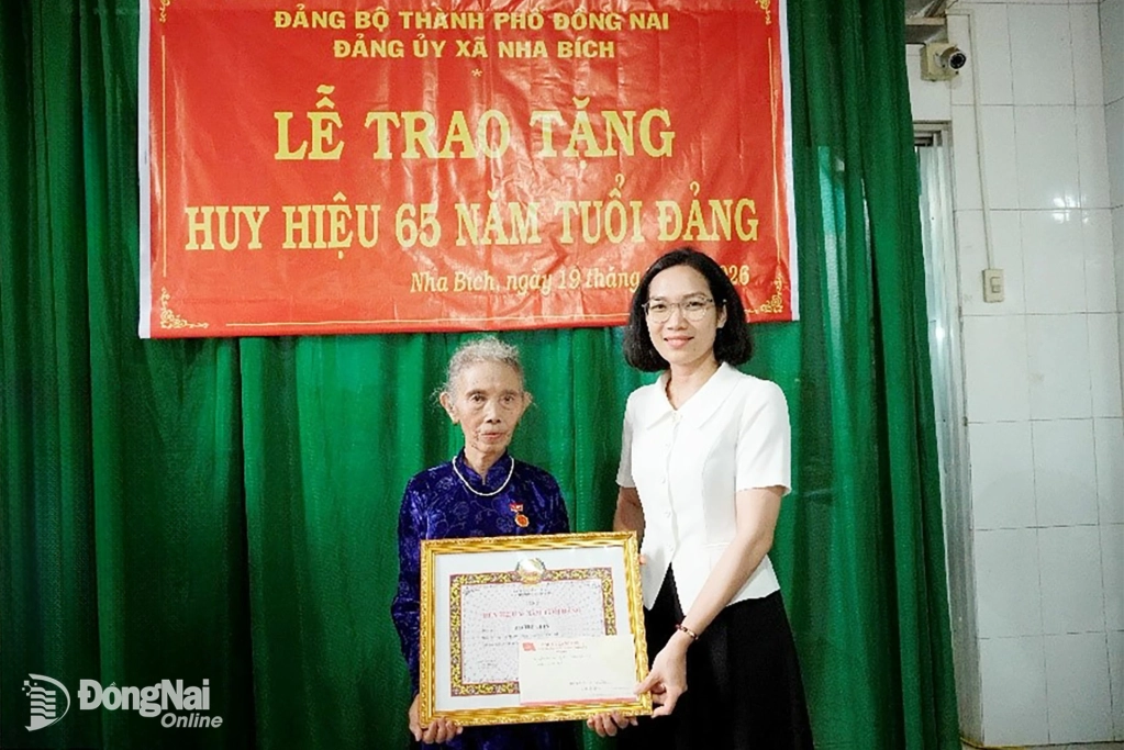 Đồng chí Nguyễn Thị Hải Vân, Phó Bí thư Thường trực, Chủ tịch HĐND xã Nha Bích trao tặng Huy hiệu 65 năm tuổi đảng cho đảng viên Hồ Thị Thìn. Ảnh: Bá Lợi